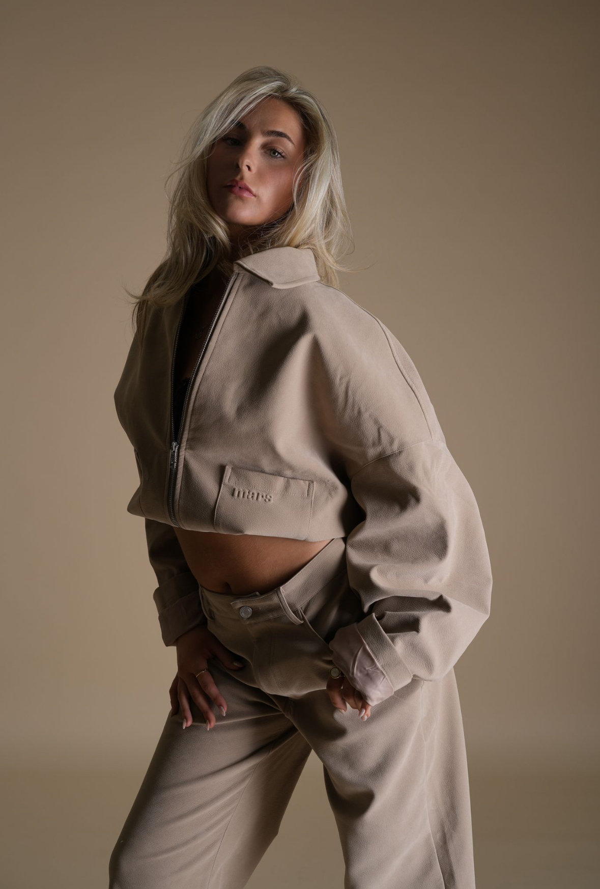 Dancer in a beige studio setting representing the confident, editorial style of Elevate Dance Studios